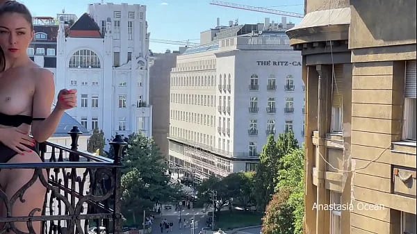 A woman undresses on a balcony in the city center. Public flashing.